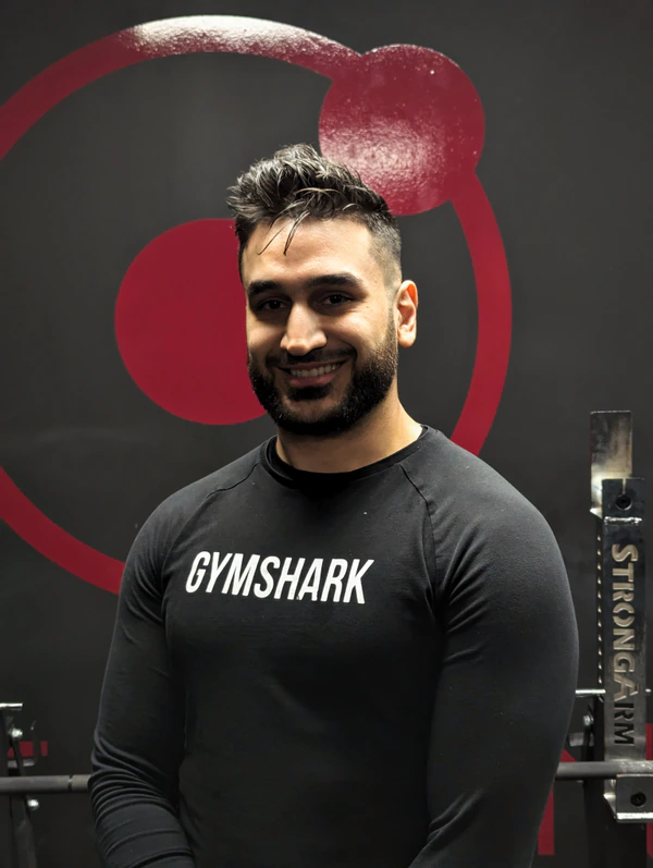 Youssef, coach at Retraine, in front of the studio logo wall in Pickering.